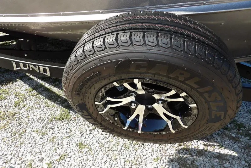 Slide: The Image of 2023 Lund 1675 Adventure SS trailer tire with Carlisle branding on gravel. - 45