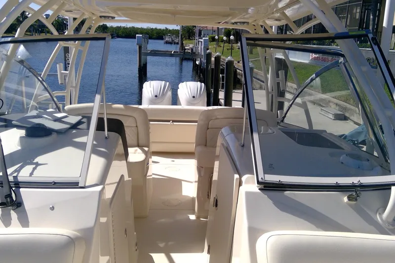 Slide: The Image of 2023 Grady-White Freedom 285 boat interior with dual engines, docked by a serene waterfront. - 32