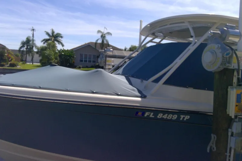 Slide: The Image of 2023 Grady-White Freedom 285 boat docked, covered, with palm trees in the background. - 50