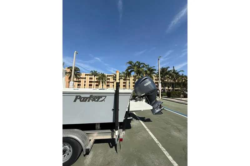 Slide: The Image of 2023 Parker 2320 Sport Cabin boat on trailer with Yamaha motor, palm trees in background. - 11