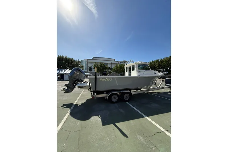 Slide: The Image of 2023 Parker 2320 Sport Cabin boat on trailer in parking lot under clear sky. - 19