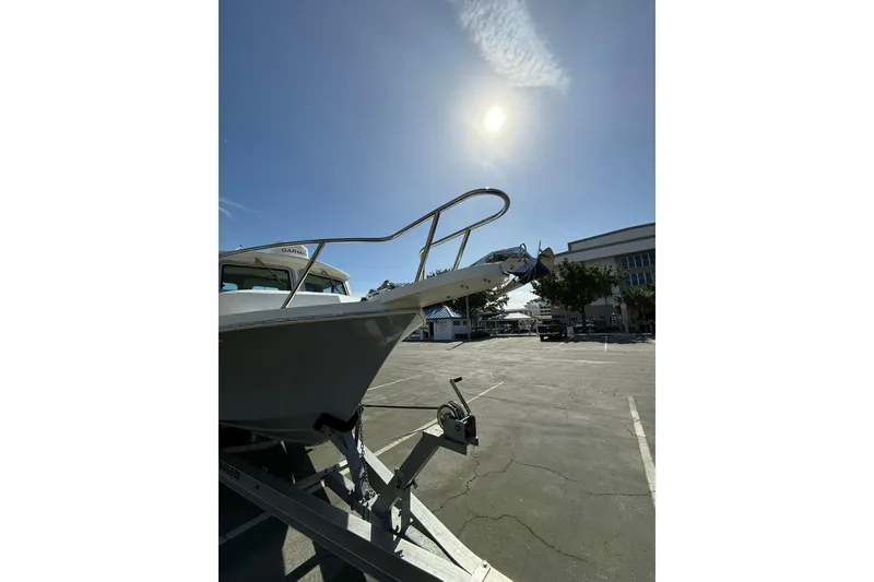 Slide: The Image of 2023 Parker 2320 Sport Cabin boat on trailer under bright sun in parking lot. - 23