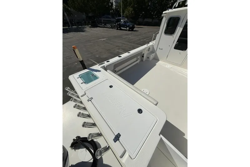 Slide: The Image of 2023 Parker 2320 Sport Cabin boat deck with rod holders and storage compartment. - 26