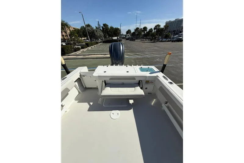 Slide: The Image of 2023 Parker 2320 Sport Cabin boat deck with seating and motor in a parking lot. - 39