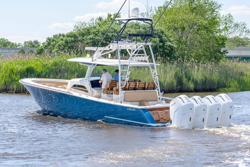 Slide: The Image of 2023 Valhalla Boatworks V-46 on water, showcasing spacious deck and seating under clear skies. - 5