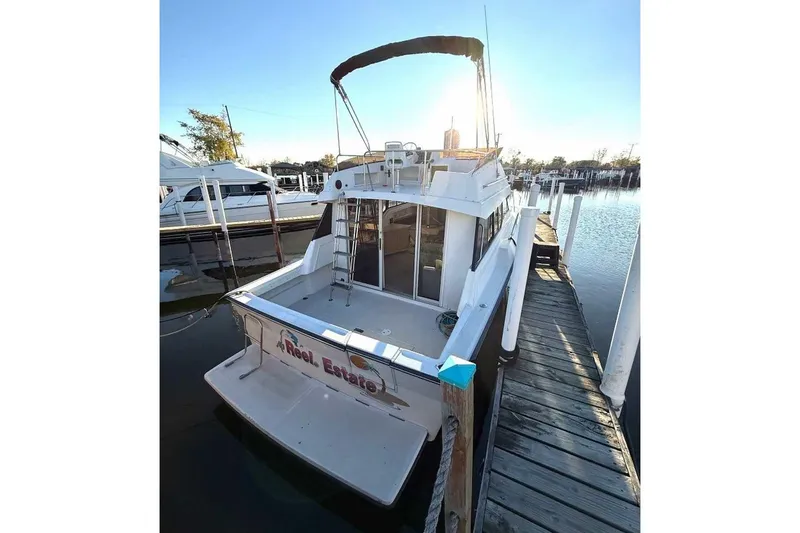 Slide: The Image of 1990 Silverton 34 Convertible docked at marina, rear view with ladder and canopy. - 19