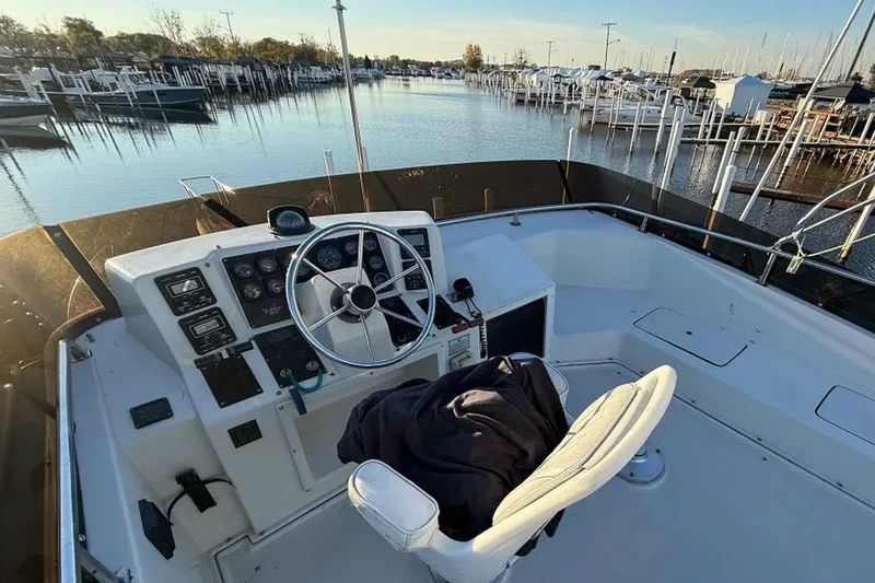 Slide: The Image of 1990 Silverton 34 Convertible boat helm with marina view, featuring steering wheel and controls. - 22