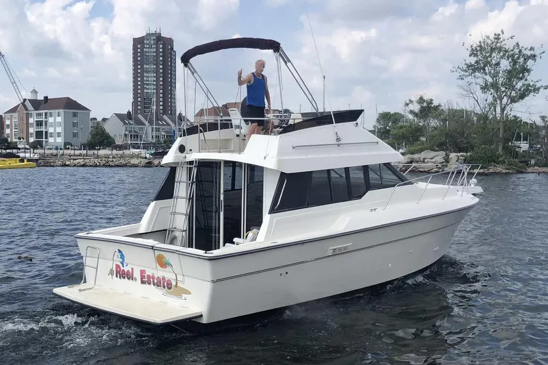 Slide: The Image of 1990 Silverton 34 Convertible boat cruising on water near urban shoreline. - 25