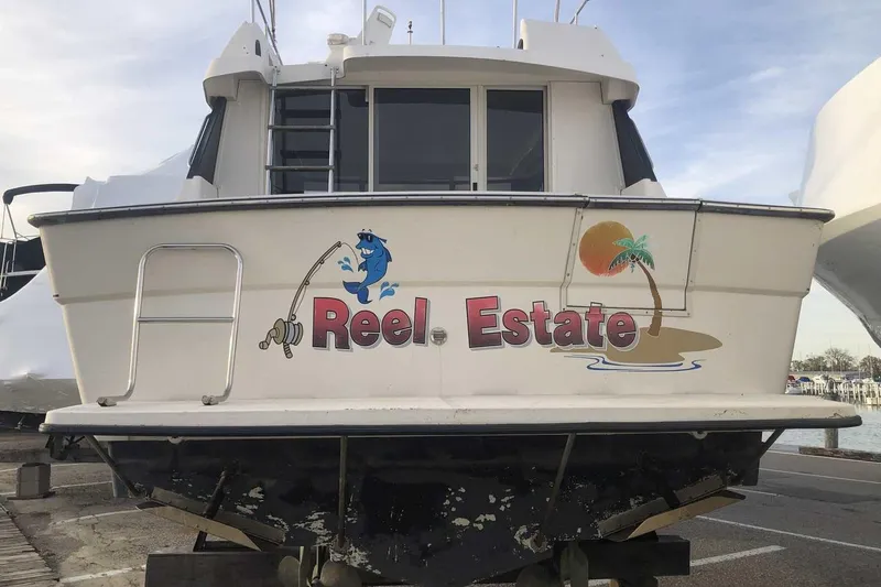 Slide: The Image of 1990 Silverton 34 Convertible boat with "Reel Estate" graphic, docked at marina. - 32