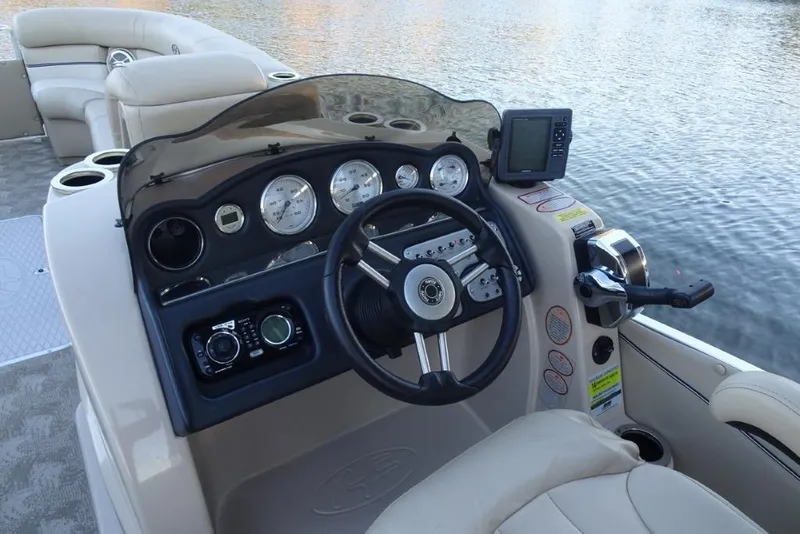 Slide: The Image of 2010 Harris Grand Mariner 230 boat dashboard with steering wheel and control panel on water. - 14