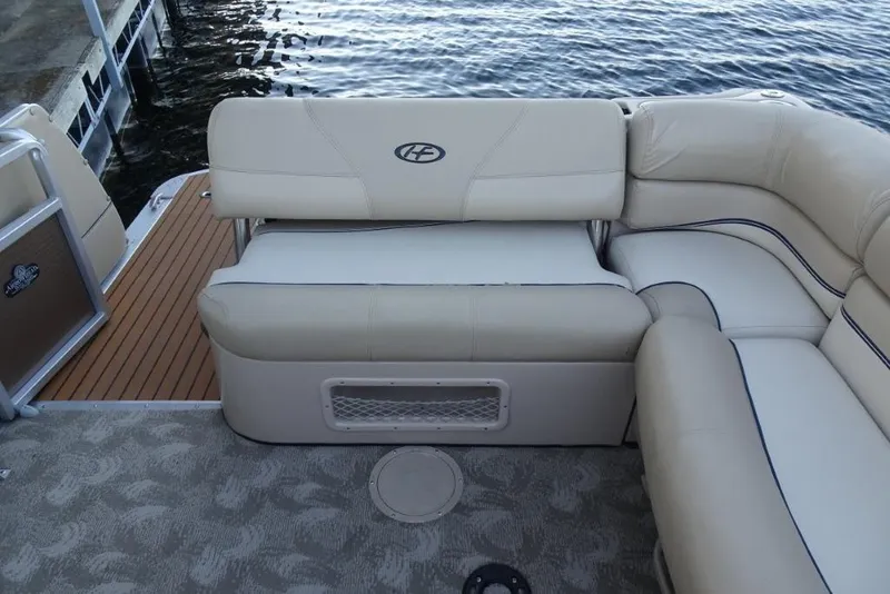 Slide: The Image of 2010 Harris Grand Mariner 230 boat interior with beige seating and wood deck by the water. - 29
