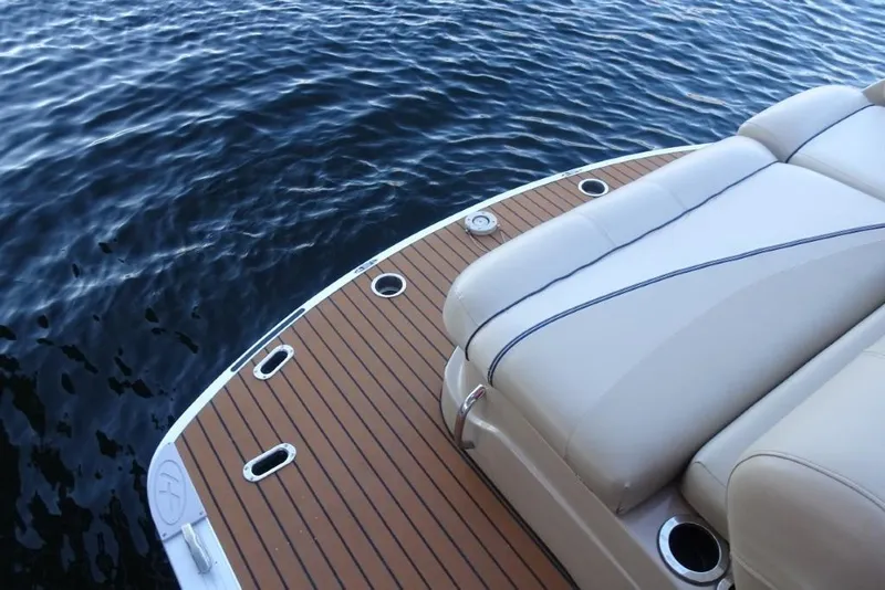 Slide: The Image of 2010 Harris Grand Mariner 230 boat with cushioned seating and wooden deck on water. - 31