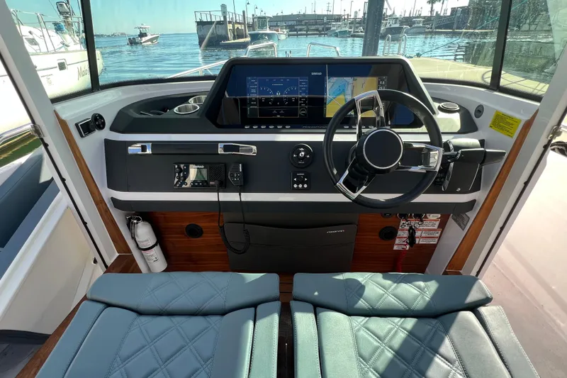 Slide: The Image of 2023 Axopar 28 Cabin Wet Bar interior with plush seating and modern helm. - 14