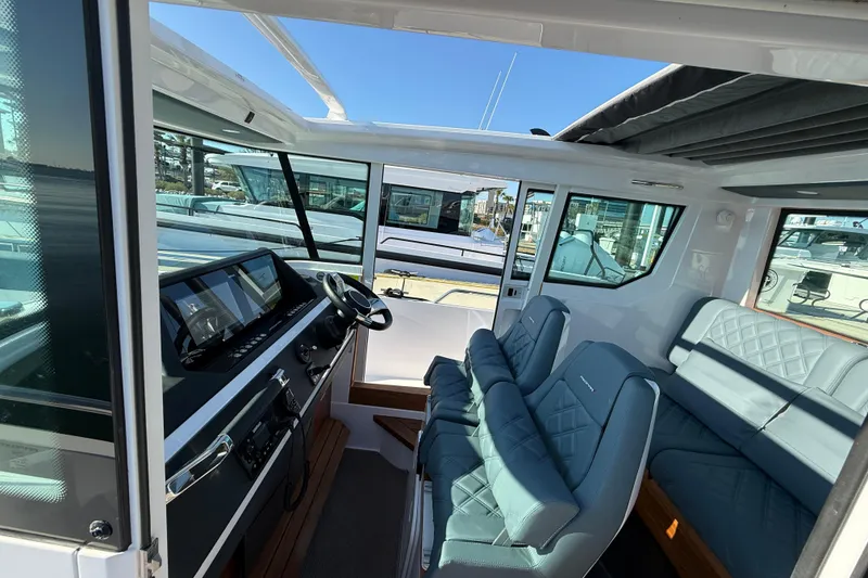 Slide: The Image of 2023 Axopar 28 Cabin Wet Bar helm with modern controls and waterfront view. - 15