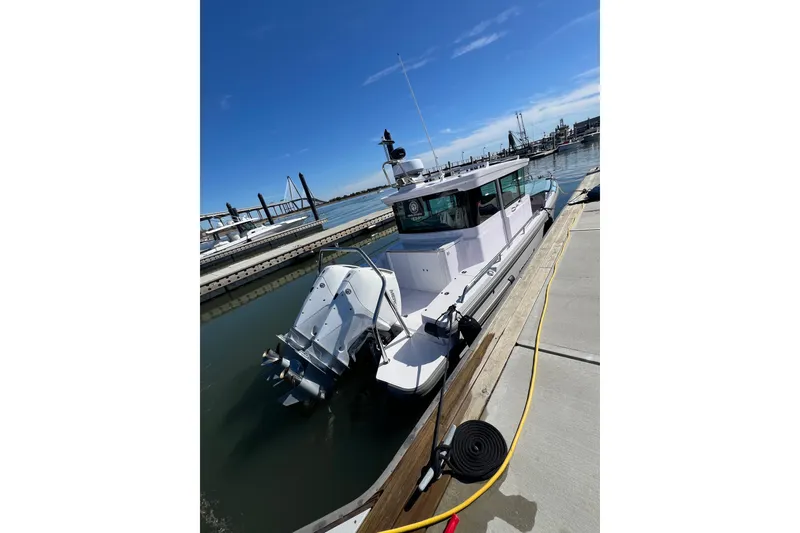 Slide: The Image of 2023 Axopar 28 Cabin Wet Bar boat docked in marina, featuring sleek design and Mercury engines. - 2