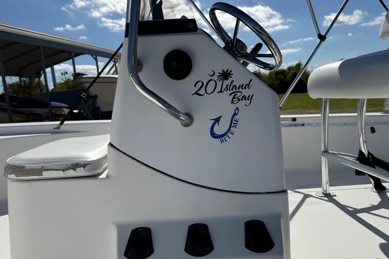 Slide: The Image of 2016 Sportsman Island Bay 20 boat console with steering wheel and logo under sunny sky. - 11