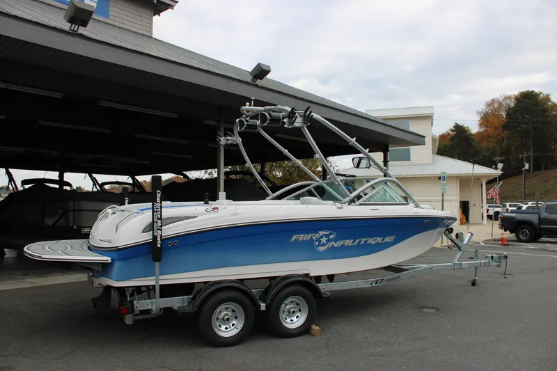 Slide: The Image of 2010 Correct Craft AIR NAUTIQUE SV 211 boat on trailer, parked outside a building. - 3
