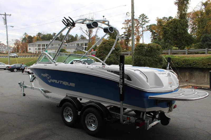 Slide: The Image of 2010 Correct Craft AIR NAUTIQUE SV 211 boat on trailer, parked outdoors. - 7
