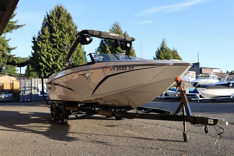 Slide: The Image of 2022 Tigé Z3 boat on trailer, parked outdoors with trees in background. - 8