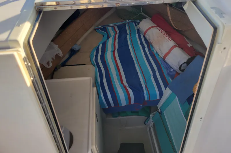 Slide: The Image of 2008 Cobia 236 Walk Around cabin interior with striped bedding and storage items. - 11