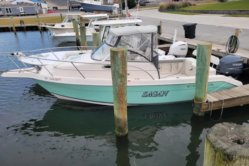 Slide: The Image of 2008 Cobia 236 Walk Around boat docked, featuring Yamaha engines and a mint green hull. - 13