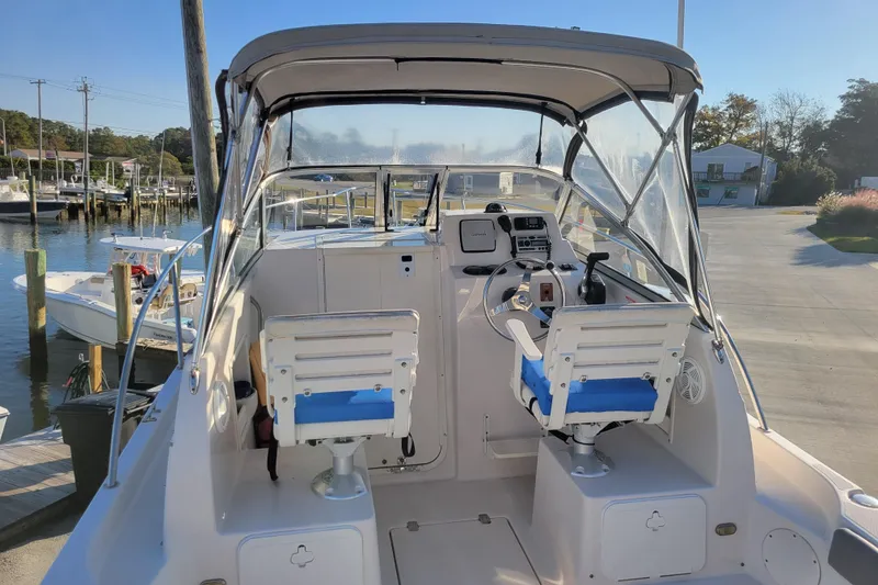 Slide: The Image of 2008 Cobia 236 Walk Around boat interior with helm and seating at marina. - 3