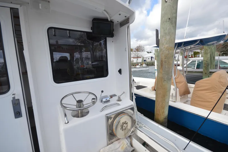 Slide: The Image of 2008 Wayne Beal EXPRESS boat docked, featuring steering wheel and nautical equipment. - 12