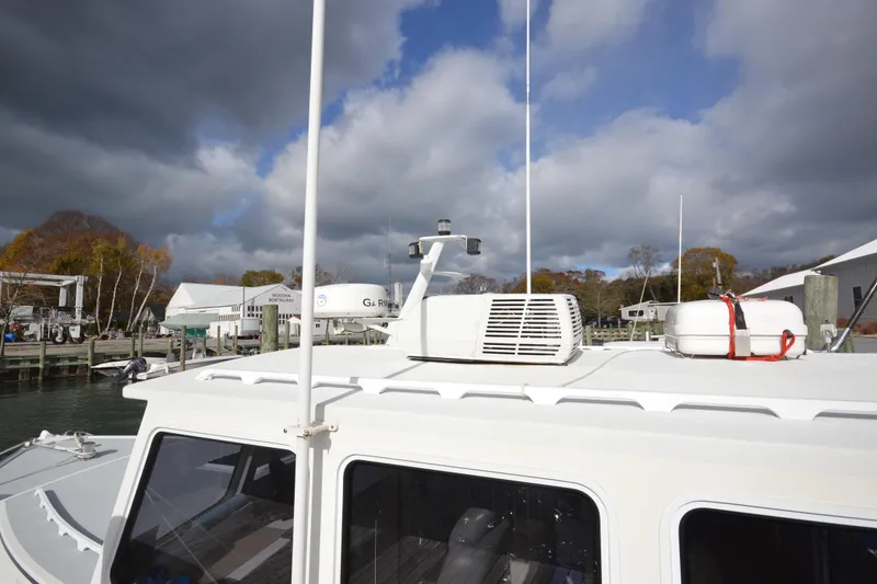 Slide: The Image of 2008 Wayne Beal EXPRESS boat docked under cloudy sky, featuring rooftop equipment. - 8