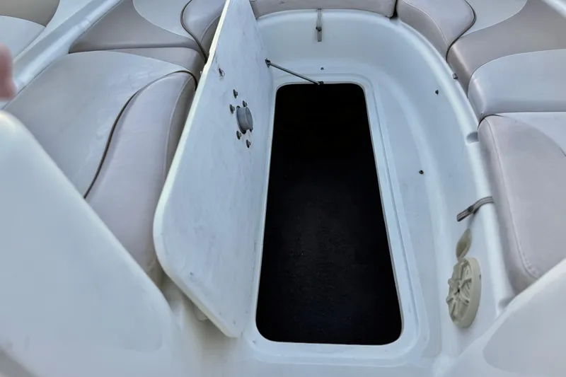 Slide: The Image of 2004 Glastron DX 235 Deckboat interior storage compartment with open hatch and cushioned seating. - 16