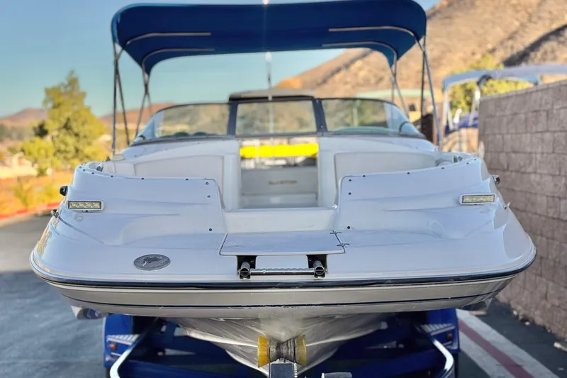 Slide: The Image of 2004 Glastron DX 235 Deckboat with blue canopy on trailer, outdoor setting. - 2