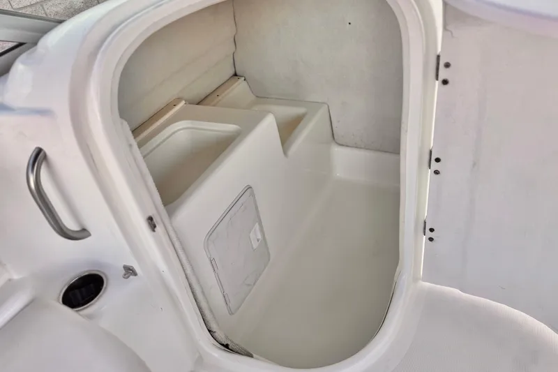 Slide: The Image of 2004 Glastron DX 235 Deckboat interior storage compartment with white finish and built-in handle. - 23