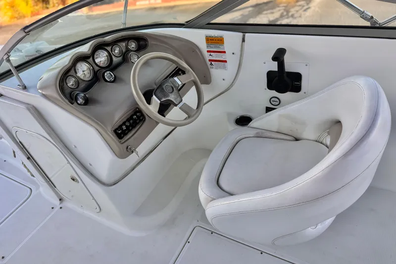 Slide: The Image of 2004 Glastron DX 235 Deckboat cockpit with steering wheel and gauges. - 26