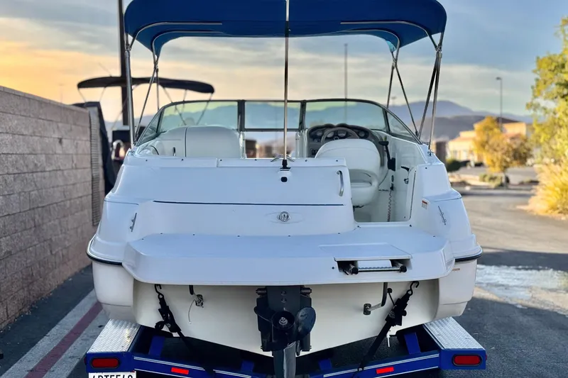 Slide: The Image of 2004 Glastron DX 235 Deckboat with blue canopy on a trailer, rear view. - 4