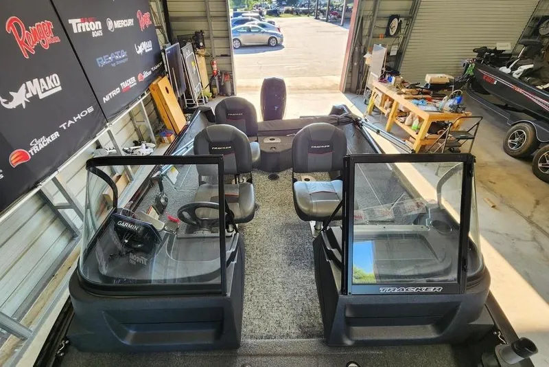 Slide: The Image of 2025 Tracker Pro Guide V-16 WT boat interior in a showroom with equipment and branding. - 11