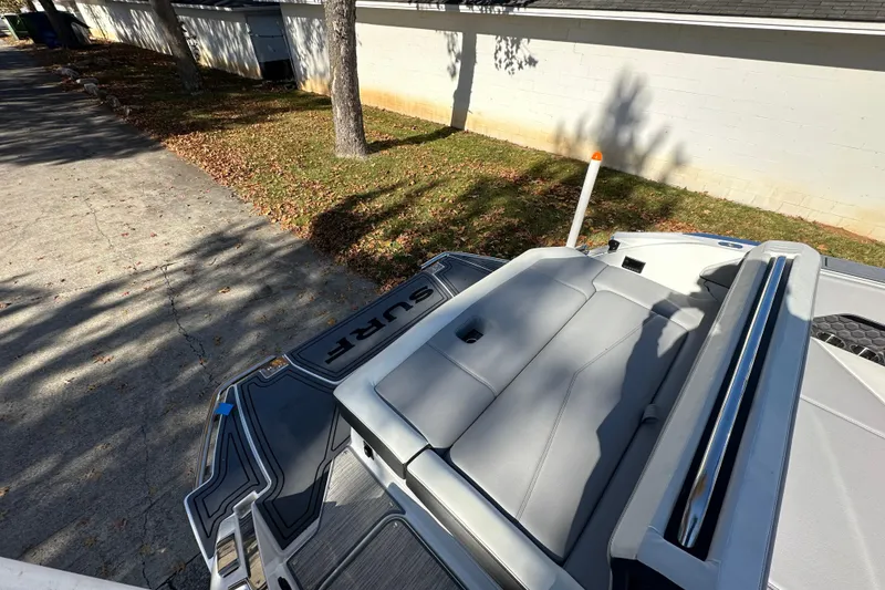 Slide: The Image of 2023 Cobalt R6 Surf boat with sleek seating, parked on a leaf-covered driveway. - 14