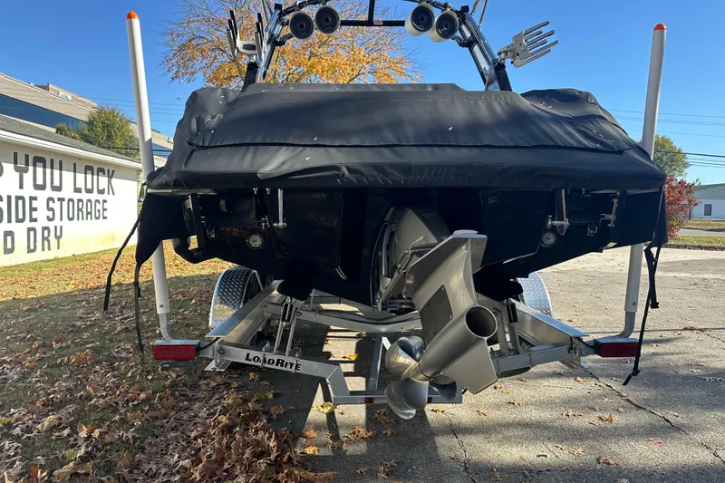 Slide: The Image of 2023 Cobalt R6 Surf boat on trailer, covered, with visible propeller and autumn leaves. - 21