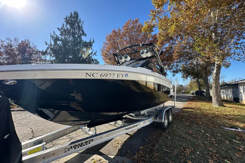Slide: The Image of 2023 Cobalt R6 Surf boat on trailer, parked under autumn trees. - 3