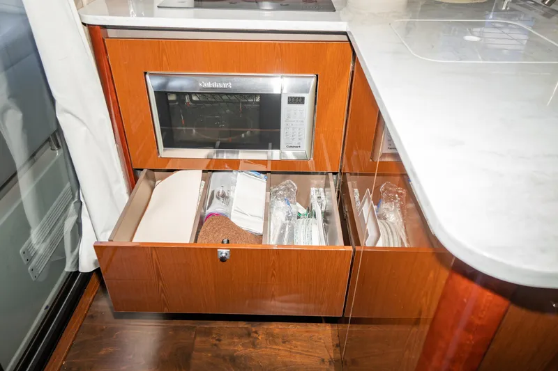 Slide: The Image of 2017 Sea Ray Sundancer 460 kitchen with microwave and open storage drawers. - 38