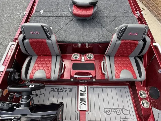Slide: The Image of 2026 Bass Cat Lynx STS boat interior with red and gray seats, cup holders, and steering console. - 14