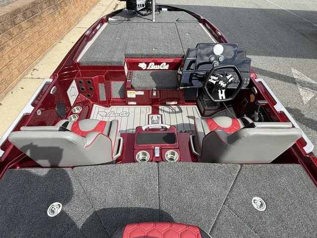 Slide: The Image of 2026 Bass Cat Lynx STS boat interior with red and gray seating, steering console, and carpeted deck. - 6