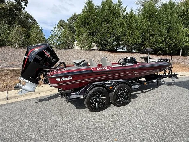 Slide: The Image of 2026 Bass Cat Lynx STS boat with trailer, parked on a road, surrounded by trees. - 4