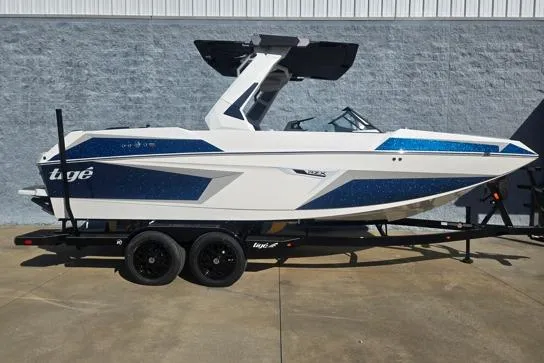 The Image of 2026 Tigé 22RZX boat on trailer, white and blue design, parked outdoors. - 1