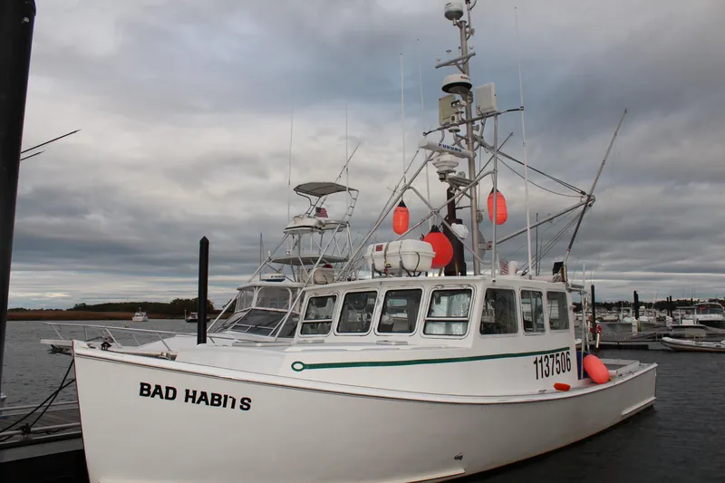 Slide: The Image of 2002 Libby 38 Downeast boat named "Bad Habit" docked at a marina. - 2