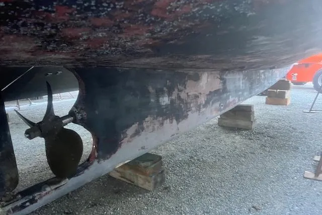 Slide: The Image of 2002 Libby 38 Downeast boat hull on blocks, showing propeller and weathered paint. - 35