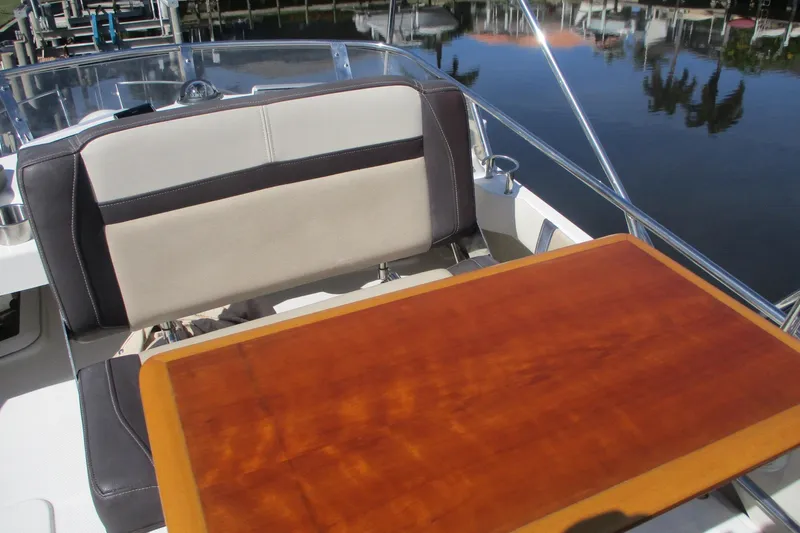 Slide: The Image of 2015 Cutwater 30 Command Bridge LE boat interior with wooden table and cushioned seating. - 21