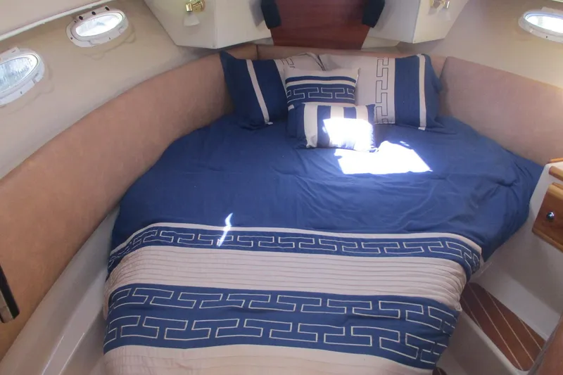 Slide: The Image of 2015 Cutwater 30 Command Bridge LE cabin with blue bedding and decorative pillows. - 35