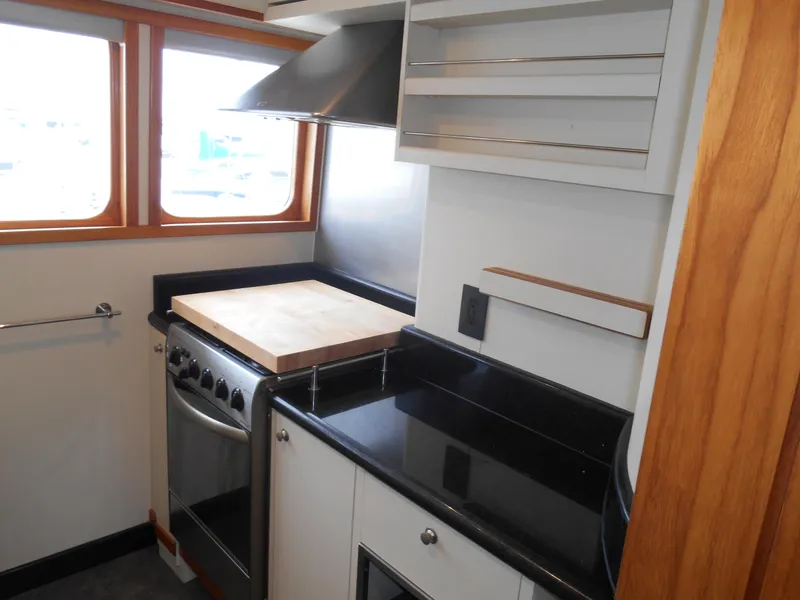 Slide: The Image of Compact kitchen in a 2005 Inace Trawler with stove, cutting board, and black countertops. - 11