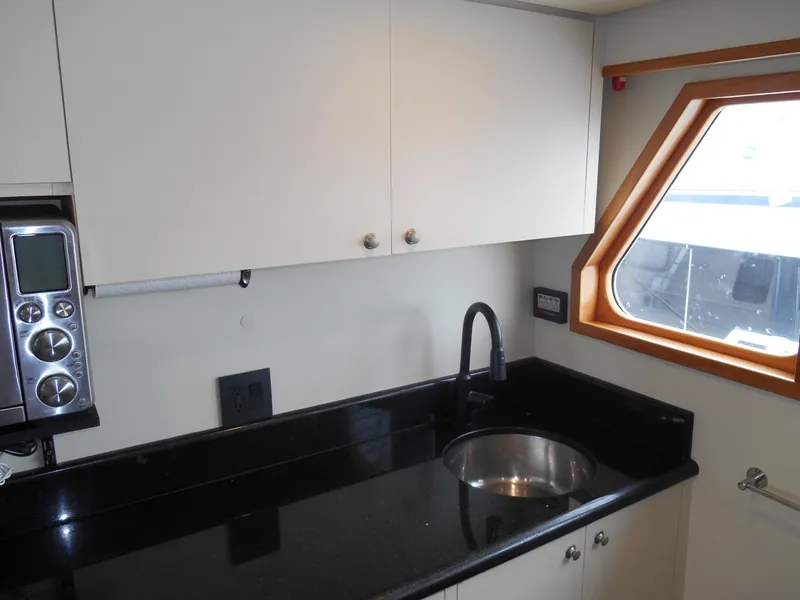 Slide: The Image of Compact kitchen area in a 2005 Inace Trawler with black countertop and stainless steel sink. - 13