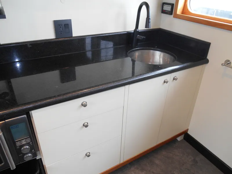 Slide: The Image of Kitchen area of a 2005 Inace Trawler with black countertop and sink. - 15