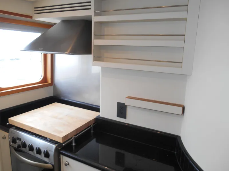 Slide: The Image of 2005 Inace Trawler kitchen with stove, cutting board, and sleek black countertops. - 16